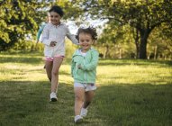 Toddler and elementary age girls running on green meadow — Stock Photo