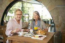 Smiling senior couple having breakfast in a cafe — Stock Photo