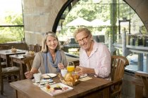 Sorridente coppia anziana che fa colazione in un caffè — Foto stock