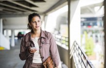 Young woman using smart phone in parking garage — Stock Photo