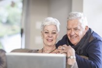 Coppia anziana guardando insieme al computer portatile — Foto stock