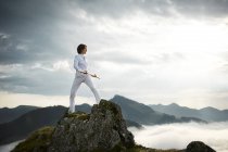 Áustria, Kranzhorn, Mulher adulta média se exercitando com vara de combate no topo da montanha — Fotografia de Stock