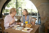 Sonriendo pareja mayor desayunando en un café - foto de stock