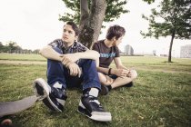 Germany, Berlin, two teenage boys sitting under a tree — Stock Photo