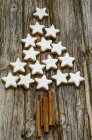 Cinnamon stars and cinnamon sticks forming shape of Christmas tree on wood — Stock Photo