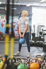 Senior woman in gym lifting kettlebell — Stock Photo