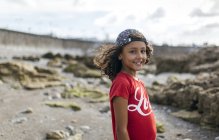 Portrait of smiling little girl on rocky beach — Stock Photo