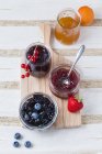 Jars of different berry and fruit  jams with ingredients on wooden chopping board — Stock Photo