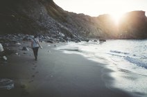 Spagna, Ortigueira, donna che cammina sulla spiaggia sabbiosa al crepuscolo — Foto stock