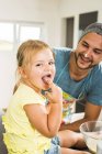 Father and daughter baking in kitchen tasting dough — Stock Photo