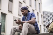 Мужчина сидит на ступеньках со смартфоном — стоковое фото