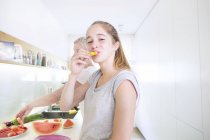 Portrait of smiling teenage girl eating melon in the kitchen — Stock Photo