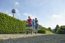 Vater schiebt Handwagen mit zwei Kindern in Kleingartenanlage — Stockfoto