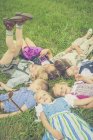 Gruppo di bambini che indossano abiti tradizionali sdraiati su un prato in cerchio — Foto stock