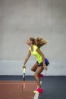 Jovem mulher jogando tênis em um centro de tênis indoor — Fotografia de Stock