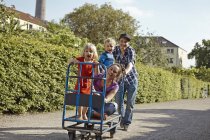 Vater schiebt Handwagen mit Familie in Kleingartenanlage — Stockfoto