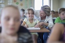 Lächelnder Lehrer im Gespräch mit Schülerin im Klassenzimmer — Stockfoto