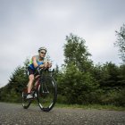 Triathlete riding on bicycle on the road — Stock Photo