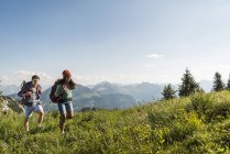 Austria, Tyrol, Tannheimer Tal, young couple hiking on alpine meadow — Stock Photo