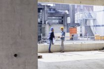 Zwei Männer mit harten Hüten unterhalten sich auf Baustelle — Stockfoto