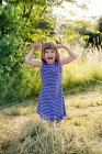 Портрет маленькой девочки, стоящей на сеновале и корчащей рожи — стоковое фото
