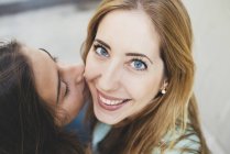 Fille embrasser jeune femme sur la joue — Photo de stock