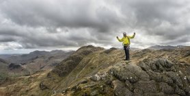 England, cumbria, lake district, langdale, harrison stickle, kletterer hält die hände oben auf dem felsen — Stockfoto