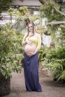 Портрет вагітна жінка, стоячи в теплиці — стокове фото