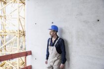 Працівник на будівельному майданчику стоїть біля бетонної стіни — стокове фото