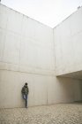 Мужчина, прислонившись к бетонной стене, смотрит на свой смартфон — стоковое фото