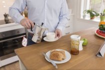 Uomo versare espresso in tazza nella sua cucina, vista parziale — Foto stock