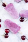 Вишневый йогурт ледяные леденцы и вишни на белом мраморе — стоковое фото