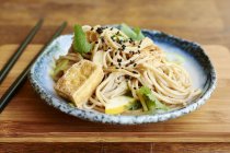 Asian noodle salad with soba noodles, tofu, green onions, yellow zucchini and coriander, garnished with black sesame seeds — Stock Photo