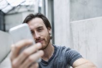 Porträt eines jungen Mannes, der auf sein Smartphone blickt — Stockfoto