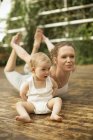 Donna che fa esercizio di yoga mentre il bambino seduto oltre — Foto stock