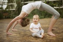Woman doing yoga exercise while  baby watching her — Stock Photo