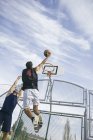 Young man playing basketball, dunking ball — Stock Photo