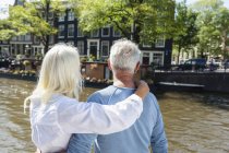 Netherlands, Amsterdam, senior couple embracing at town canal — Stock Photo