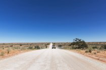 Намибия, Калахари, внедорожник, движущийся по гравийной дороге днем — стоковое фото