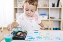 Portrait of little boy painting with watercolours — Stock Photo