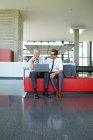 Двоє усміхнених бізнесменів працюють на ноутбуці в офісному вестибюлі — стокове фото