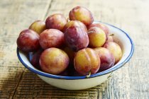 Enamel bowl of plums — Stock Photo