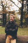 Retrato de jovem sorridente com braços cruzados no parque outonal — Fotografia de Stock