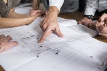 Imagem cortada da mão apontando no plano de construção — Fotografia de Stock