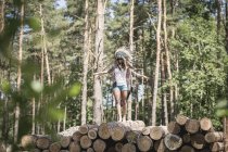 Junge Frau gibt sich als Indianerin aus, die auf Holzstapeln balanciert — Stockfoto