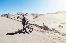 Cile, donna che spinge una mountain bike nella Valle della Luna nel deserto di Atacama — Foto stock