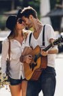 Paar auf der Straße mit Gitarre und Blumen — Stockfoto