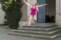 Retrato de mulher loira feliz pulando no ar depois de deixar a igreja — Fotografia de Stock
