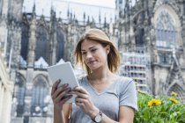 Германия, Кельн, портрет молодой женщины с мини-планшетом перед Кёльнским собором — стоковое фото