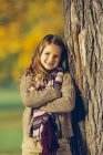 Portrait de fille souriante appuyée sur le tronc d'arbre — Photo de stock
